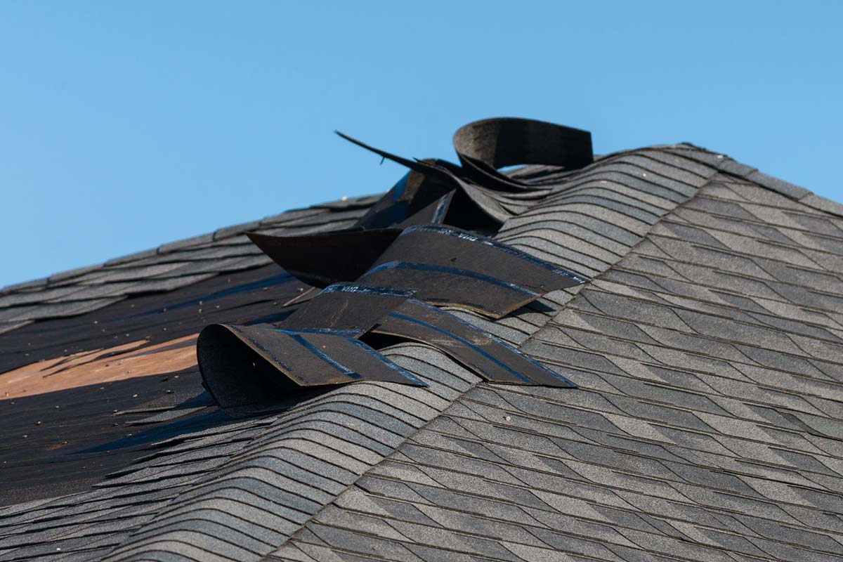 An aging asphalt shingle roof showing curled and missing shingles